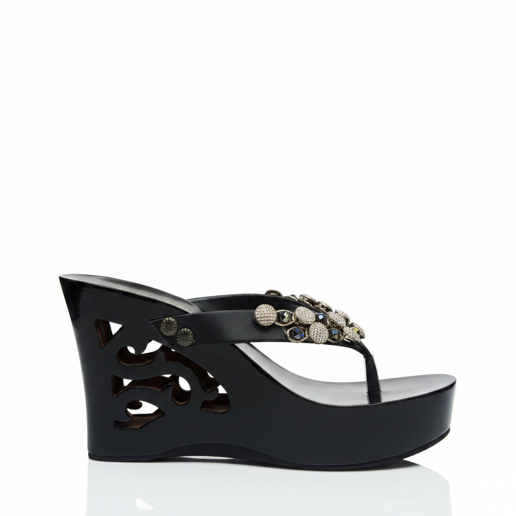 A single black wedge sandal with a cutout platform sole and a decorative embellished toe strap, shown from a side profile on a white background.