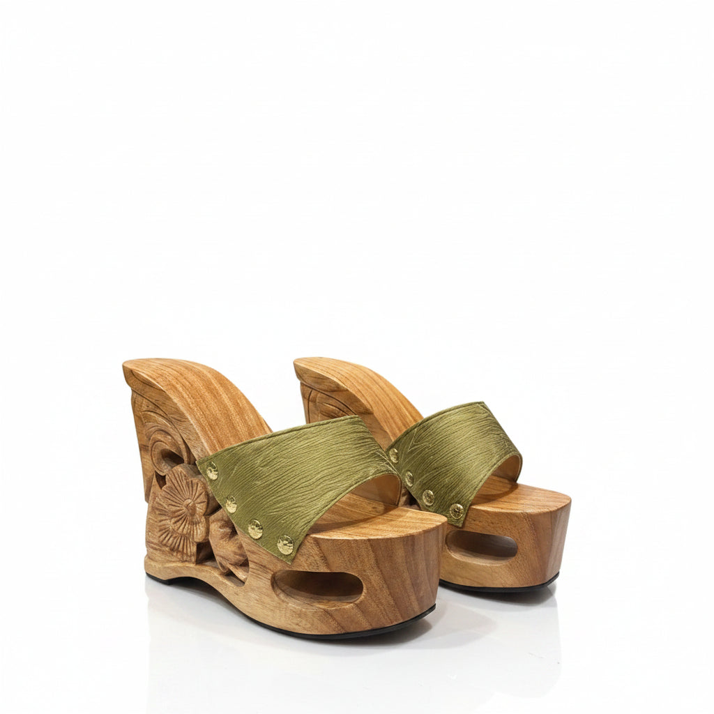 A pair of wooden platform wedge sandals with carved floral details on the heel and olive green woven straps, shown against a plain white background.