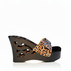A single women's wedge sandal shown in side profile on a plain white background. The shoe has a glossy black wedge heel and platform with cutout details, a leopard-print strap in tan, brown, and black, and a blue rhinestone-embellished buckle closure.