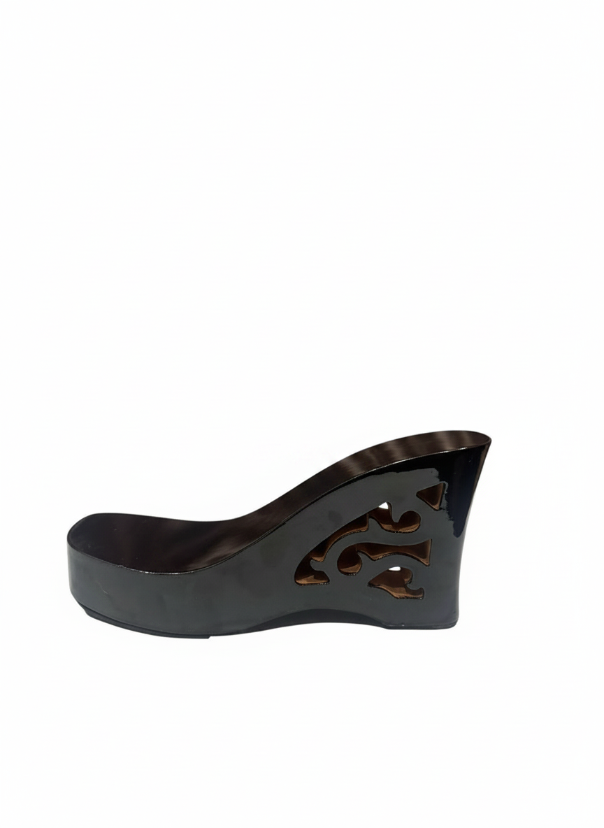 A single black wedge shoe with a glossy finish and decorative cutout detailing on the side, shown against a plain white background.